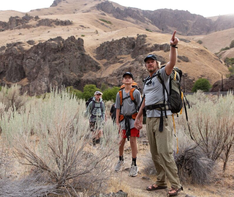 Two students following an NCOAE instructor on a hike.