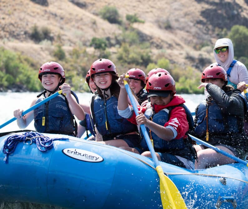 A group of teenagers whitewater paddling.