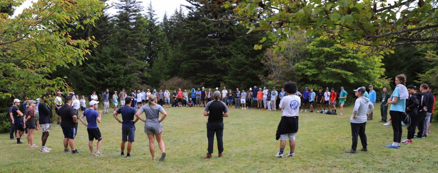 A group of students and instructors standing in a circle.