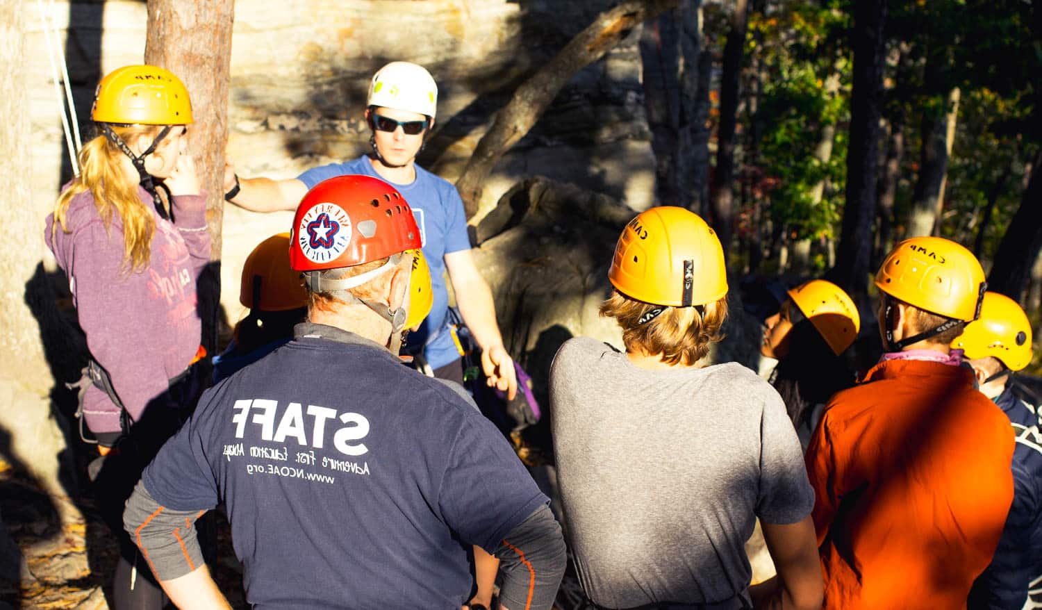 A group of people learning how to rock climb.