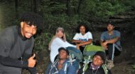 A group of HBCU students posing for a picture during a Wilderness Orientation in the woods.