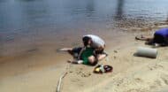 Two people laying on the sand next to a body of water.