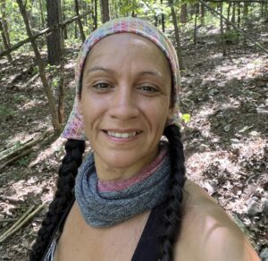 A woman wearing a head scarf in the woods.