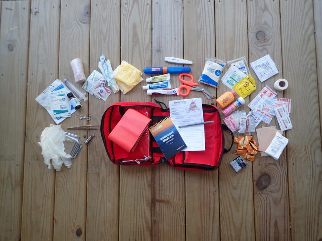 A first aid kit is laid out on a wooden floor.