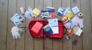 A first aid kit is laid out on a wooden floor.