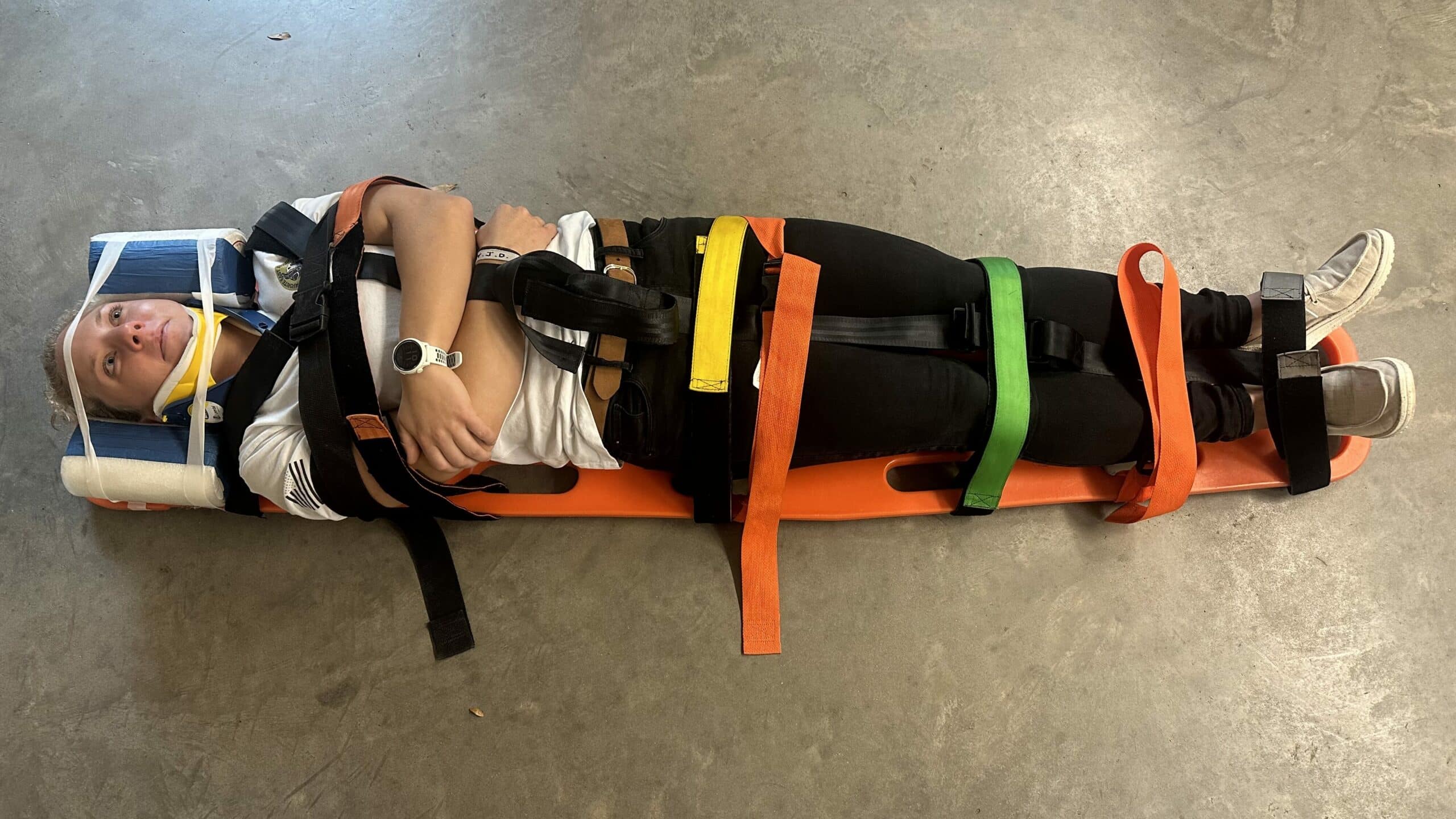 Patient on a long spine board practicing for spinal immobilization in the backcountry.