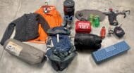 The camping contents of a backpack on a concrete floor.