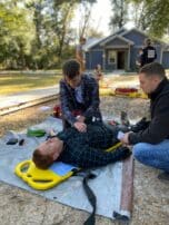 Wilderness Medicine training at NCOAE, man checking for heartbeat with stethoscope.