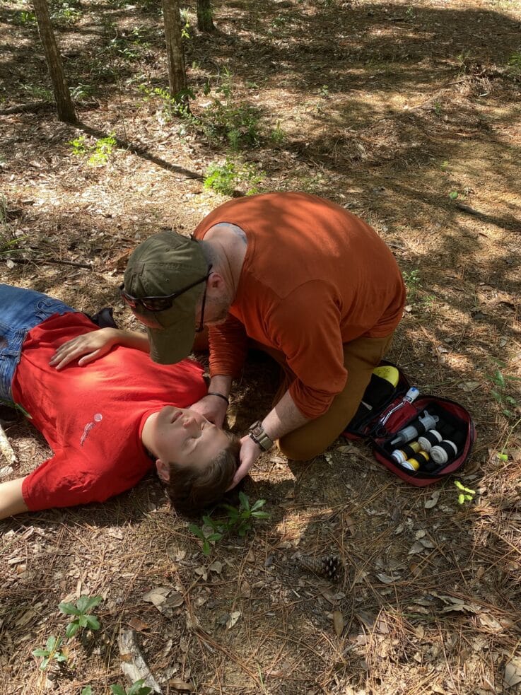 Man assessing patient during NCOAE wilderness medicine training