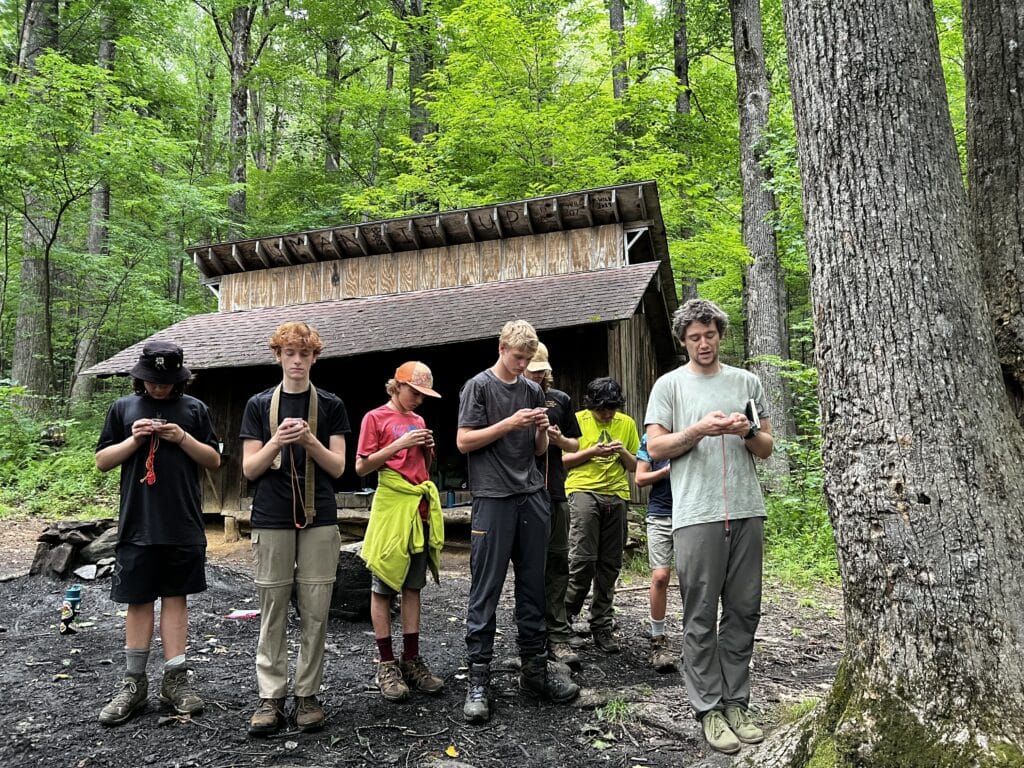 Young campers standing outside lean-to in the woods
