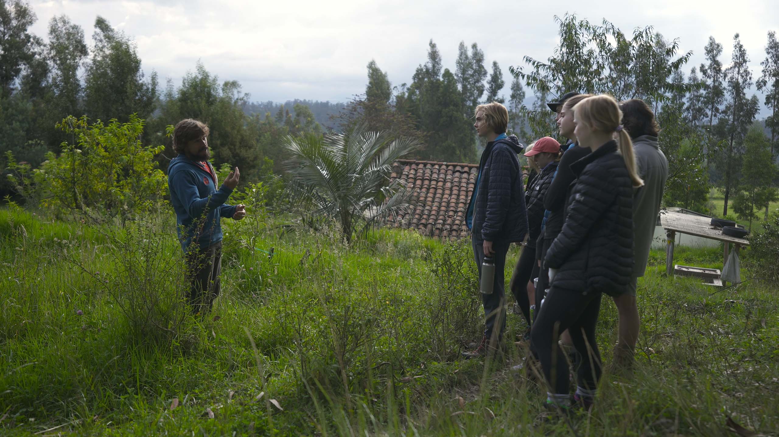 high school students taking a class outside in a field in ecuador.